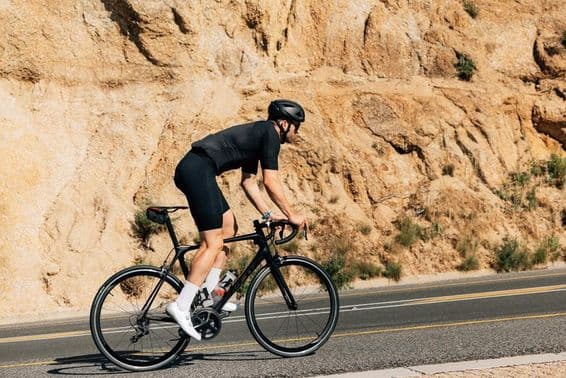 Cycliste en tenue sportive noire engagé dans un entraînement intense en plein air.