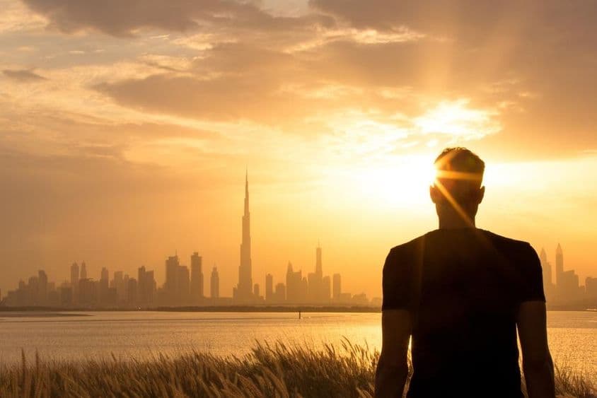 Silhouette d'un homme regardant la magnifique ligne d'horizon de la ville au coucher du soleil.