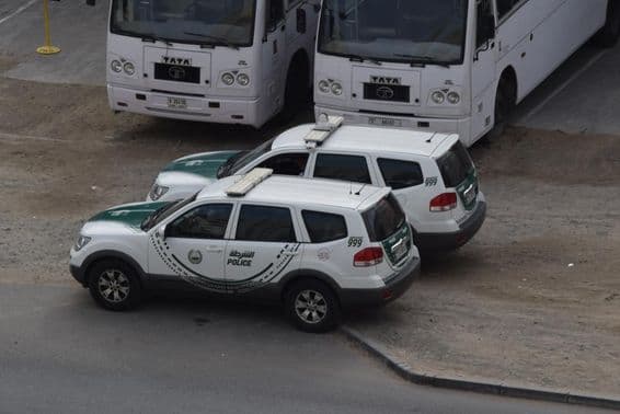Deux voitures de police de Dubaï garées devant deux bus à Al Quoz, Dubaï.