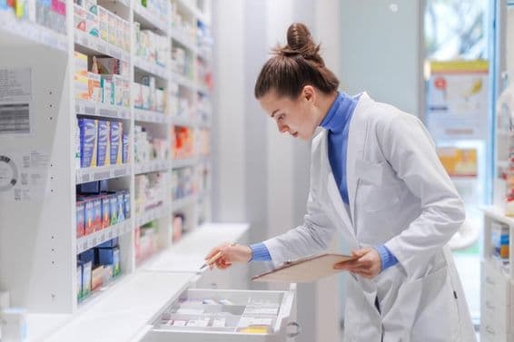 Jeune pharmacien vérifiant le stock de médicaments dans une pharmacie.