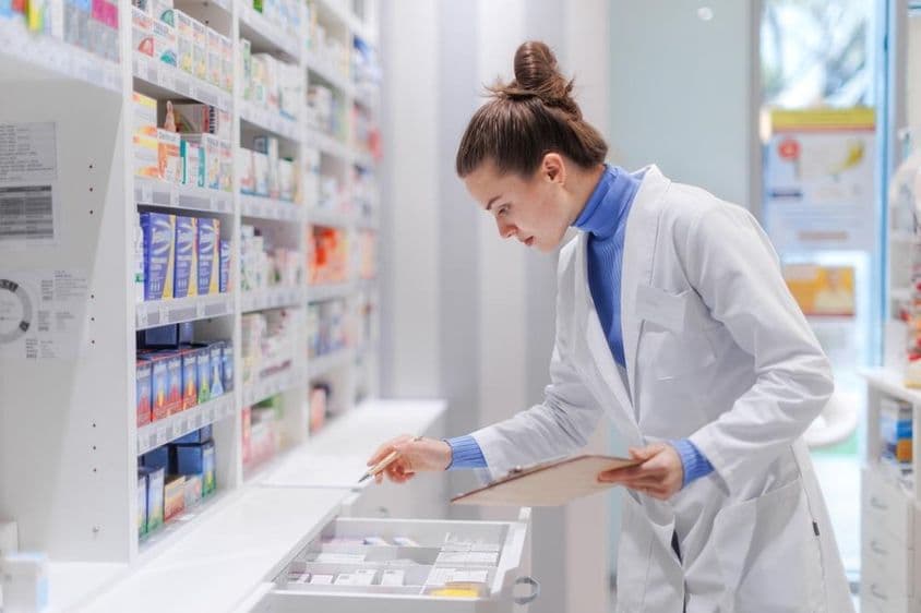 Jeune pharmacien vérifiant le stock de médicaments dans une pharmacie.