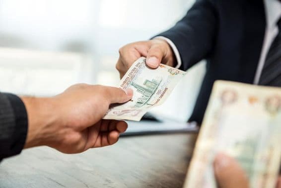 Homme d'affaires remettant de l'argent, dirhams, à un autre homme d'affaires.