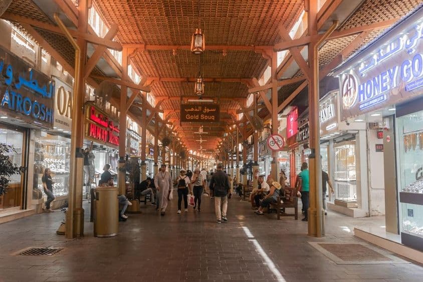 Touristes achetant et explorant le marché de l'or de Dubaï.
