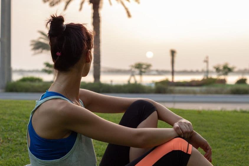 Jeune fille se reposant après le yoga dans un parc sur la Corniche d'Abu Dhabi.