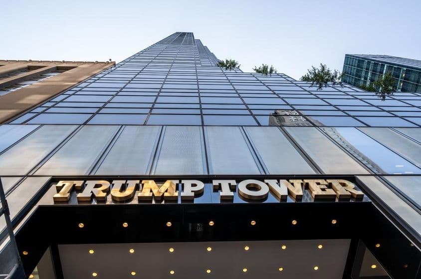 Photo iconique de l'entrée de la Trump Tower mettant en valeur l'enseigne métallique dorée.