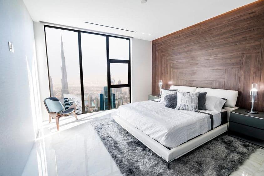 Chambre de luxe avec plafond blanc et boiseries, surplombant le centre-ville de Dubaï.