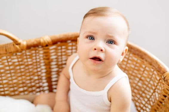 Un bébé dans un berceau tissé à la maison.