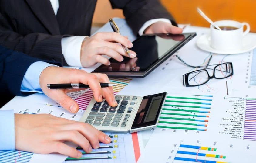 Graphiques, calculatrice, tablette, mains studieuses étudiant les données.