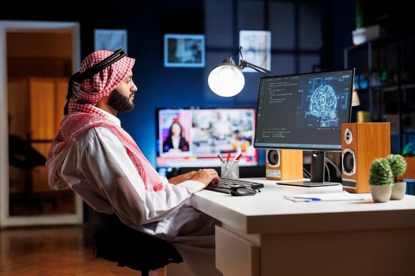 Un homme professionnel vêtu de tenue arabe travaillant sur une interface utilisateur futuriste.