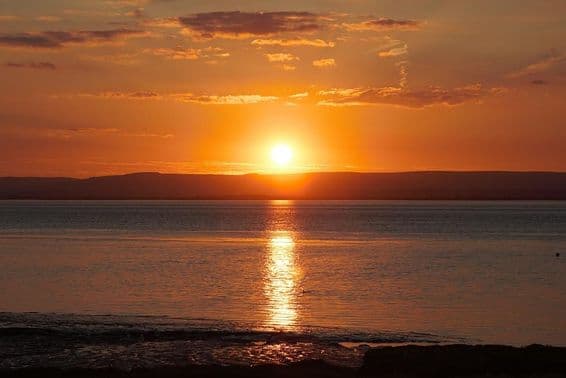 Coucher de soleil reflétant sur l'eau et les nuages durant le solstice d'été.