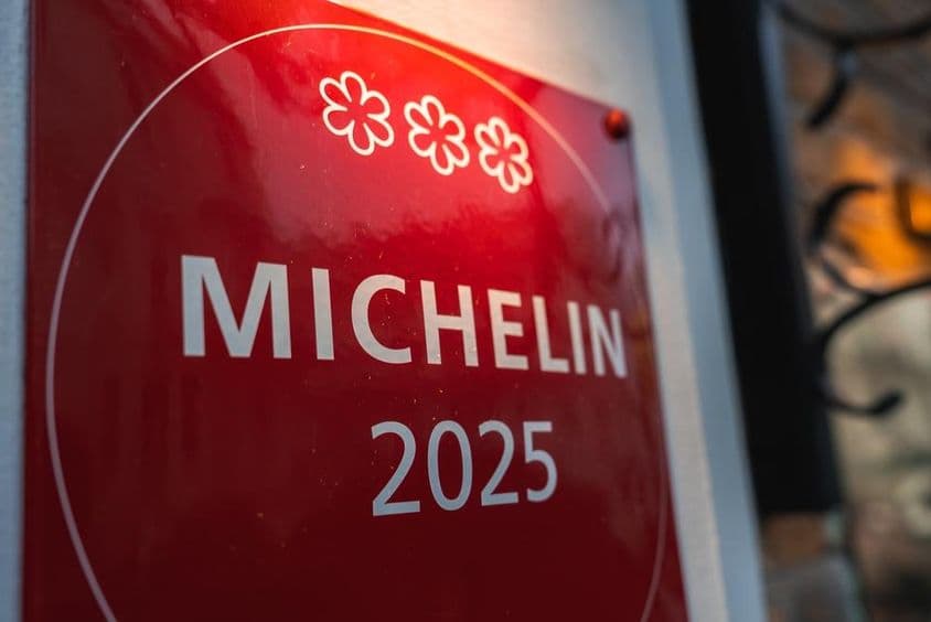Une plaque commémorative rouge avec trois étoiles Michelin 2025.