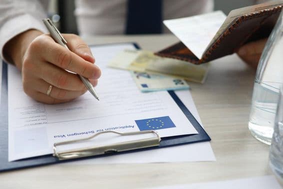 Un homme tenant un passeport et saisissant des informations personnelles sur une demande de visa Schengen.