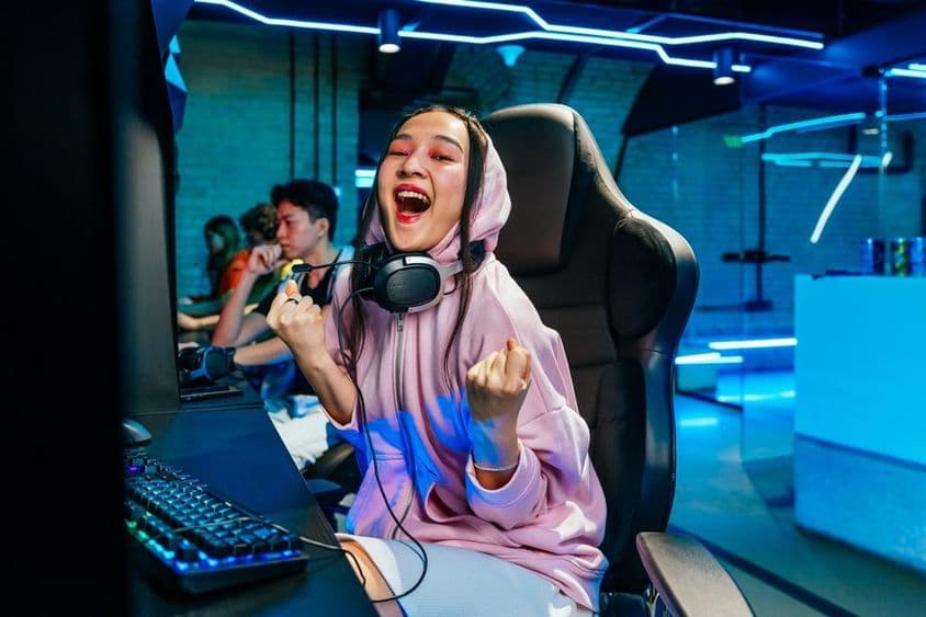 Jeune femme asiatique jouant aux jeux vidéo dans un cybercafé.