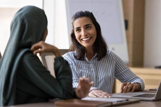 Femme d'affaires hispanophone conversant avec une collègue arabe.
