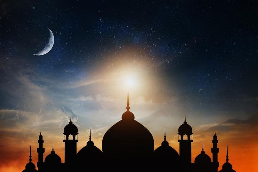 Dômes de mosquée contre un ciel bleu crépusculaire profond avec un croissant de lune en arrière-plan.