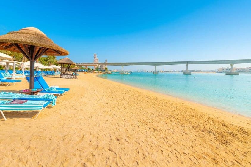 Sur une plage de sable du golfe Persique, le monorail de l'île Palm Jumeirah traverse la mer à Dubaï.