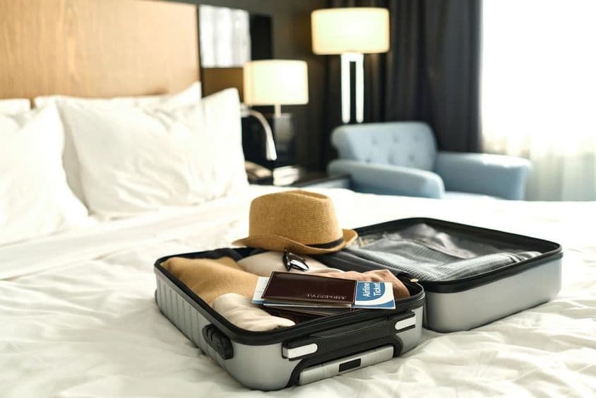 Valise remplie avec passeport et billets sur un lit.