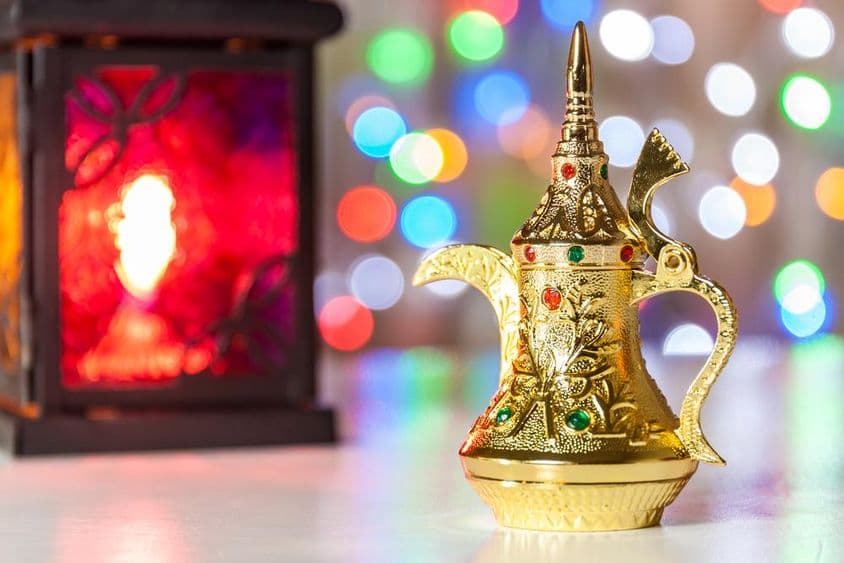 Cafetière arabe et lampe avec lumières colorées et floues en arrière-plan.