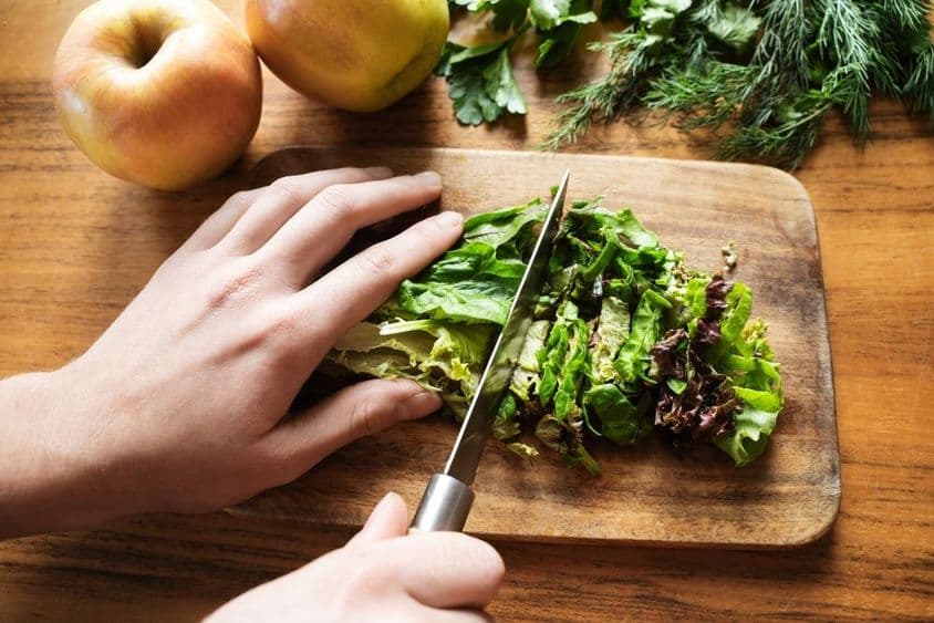 mains féminines préparant une salade pour le dîner.