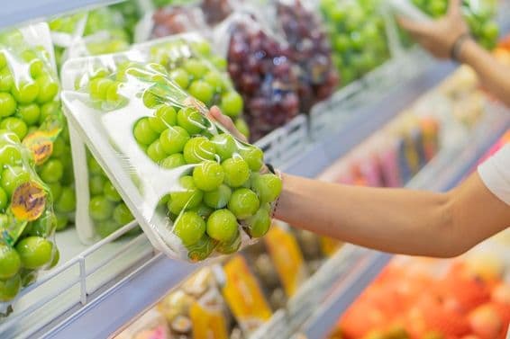 Étagères remplies de divers fruits, y compris des raisins rouges et d'autres produits emballés.