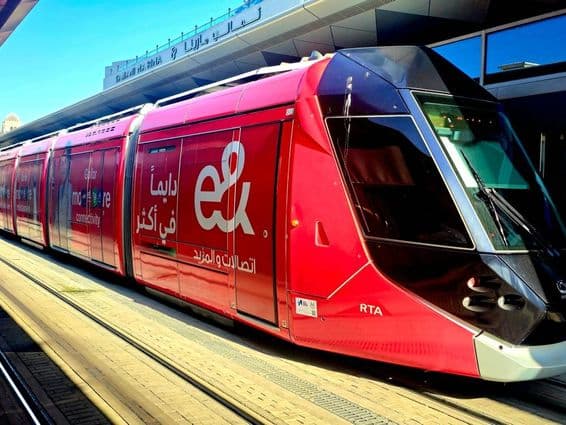 Un tram rouge stationné sur une plateforme avec de grandes fenêtres et un design élégant.