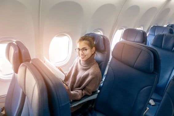 Femme asiatique lisant un magazine dans un avion.