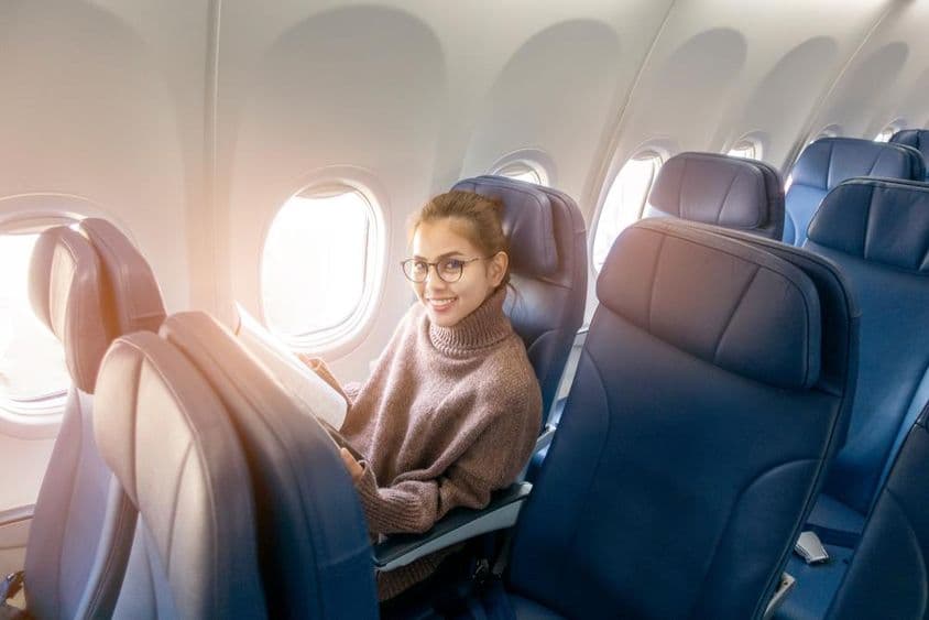 Femme asiatique lisant un magazine dans un avion.