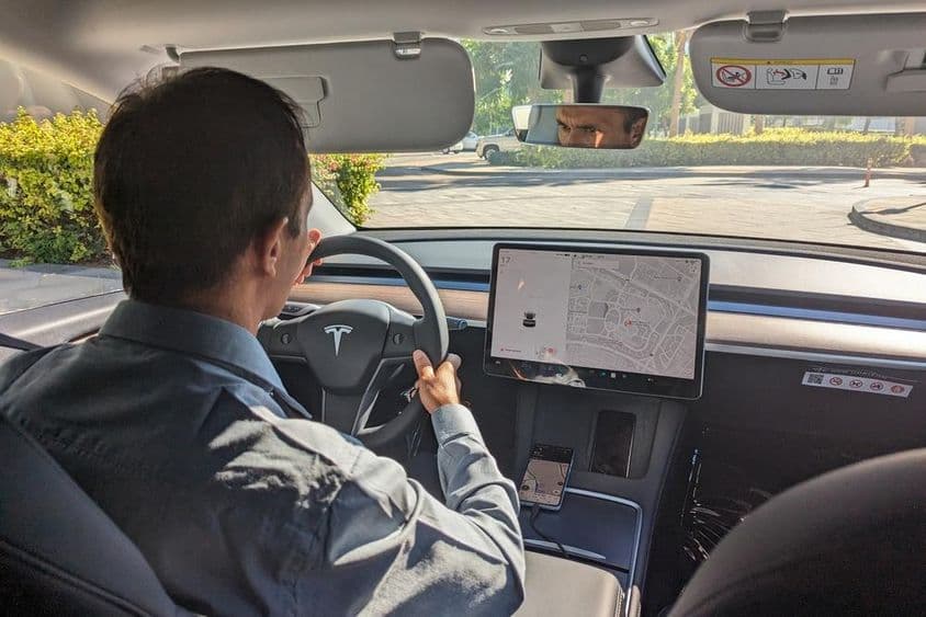 Conducteur à Dubaï conduisant une voiture Tesla sur une route urbaine.
