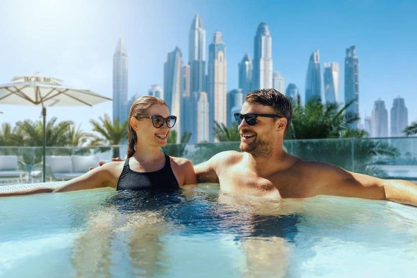 Jeune couple heureux se relaxant dans un jacuzzi extérieur dans un hôtel de Dubaï.