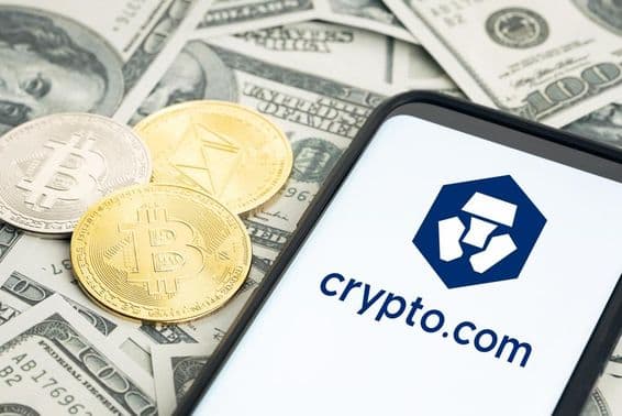 Logo de Crypto.com, billets de dollar, pièces de Bitcoin et Ethereum visibles.