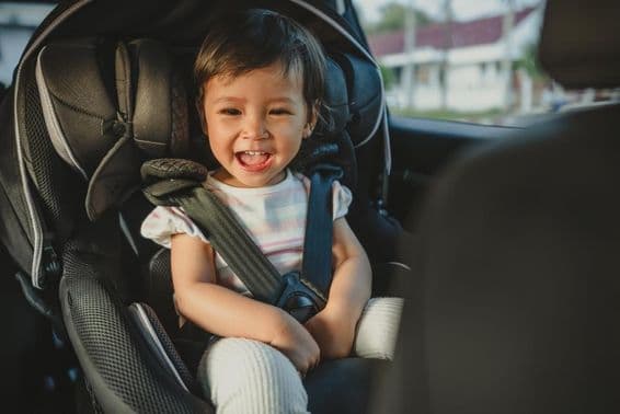 Enfant heureux assis dans un siège auto.