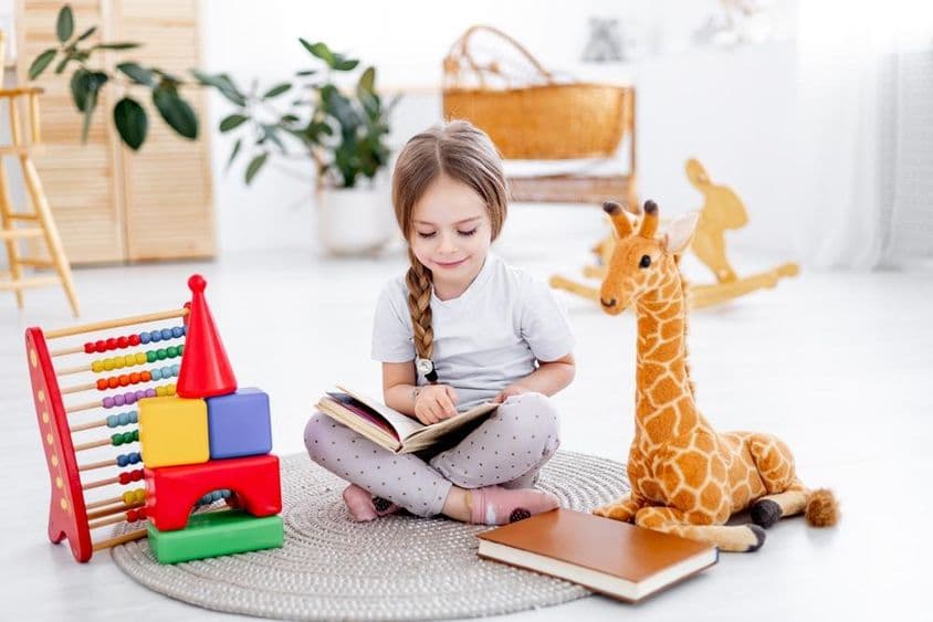 Une petite fille parmi des jouets dans une chambre d'enfants lumineuse.