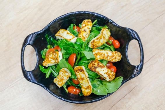Salade de fromage avec feuilles de roquette et tomates cerises.