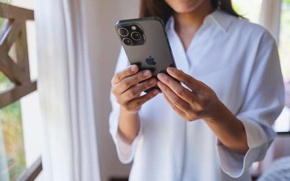 Une femme utilisant un iPhone 15 Pro Max à la maison.