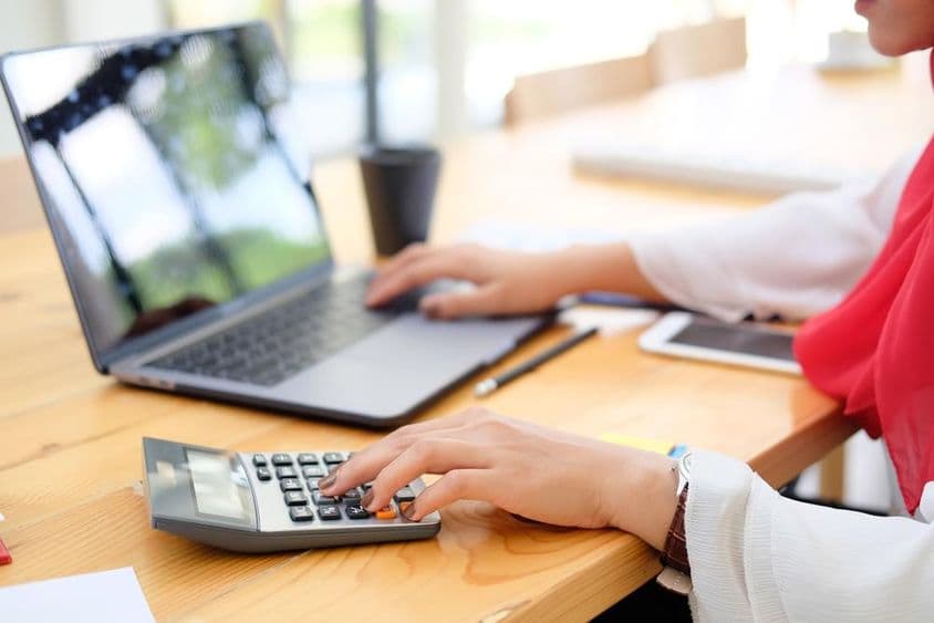 Travailleuse à Dubaï calculant des données financières avec une calculatrice.