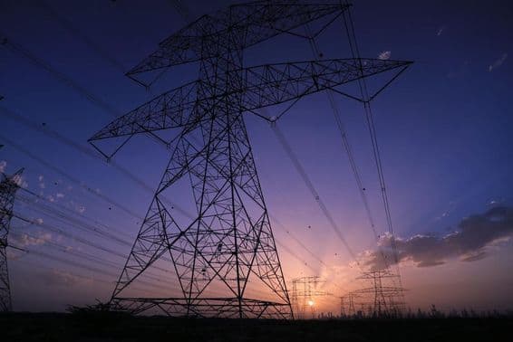 Tours haute tension sous le coucher du soleil avec une vue sur le panorama urbain de Dubaï.