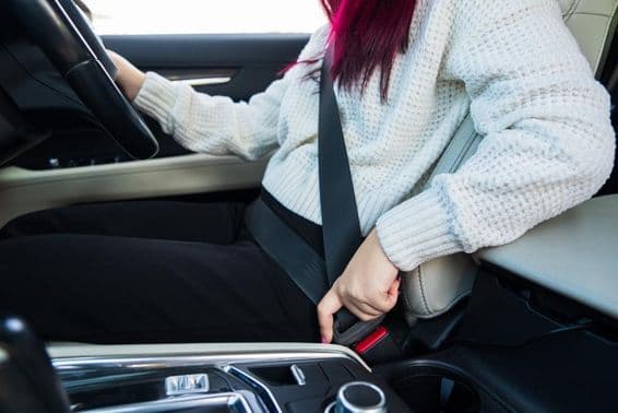 Conductrice bouclant sa ceinture de sécurité.