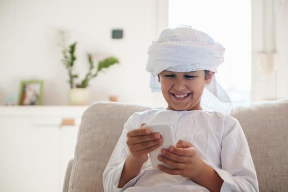 Garçon arabe utilisant un smartphone à la maison.