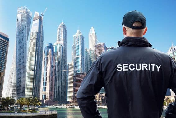 Agent de sécurité masculin regardant le paysage de la ville de dos.