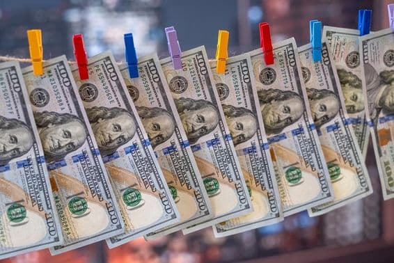 Un billet de 100 dollars US suspendu à une corde à linge avec des pinces en bois.