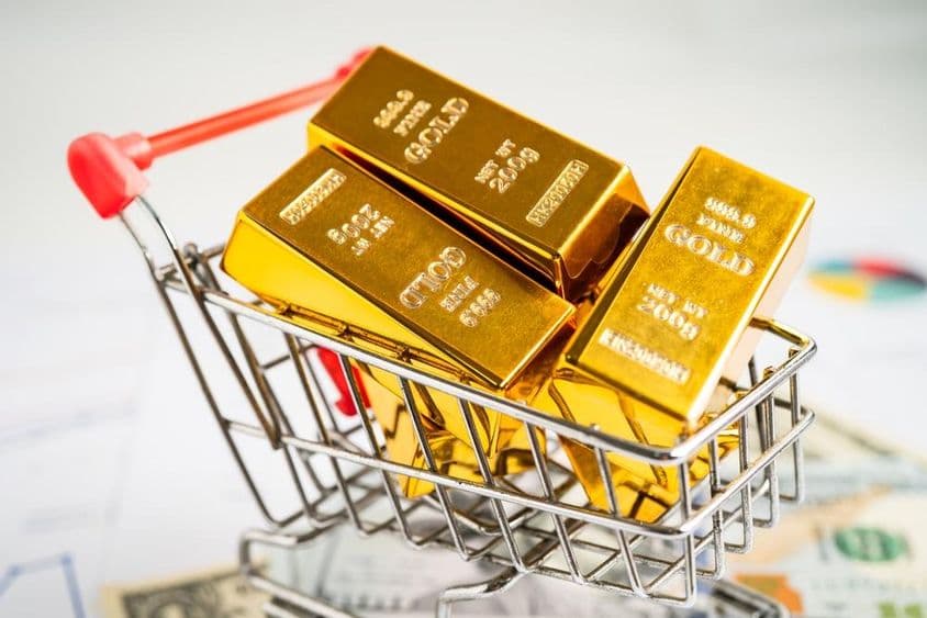Lingot d'or dans un caddie sur des billets de dollar américain.