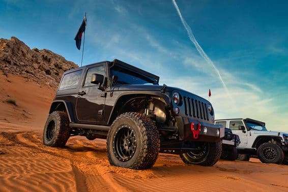 Jeep Wrangler en aventure tout-terrain sur une dune de sable dans le désert rouge de Dubaï.