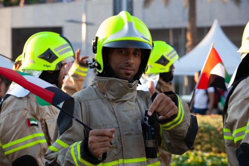 Pompiers des UAE marchant avec le drapeau des Émirats lors de la fête nationale.