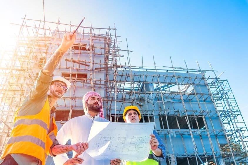 Équipe d'ingénieurs inspectant des plans de construction sur un chantier.