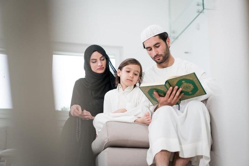 Jeunes parents et un petit garçon lisant un livre.