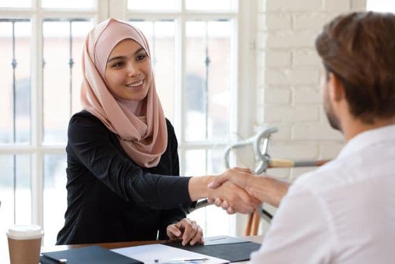 Responsable RH arabe en hijab serrant la main d'un candidat masculin.