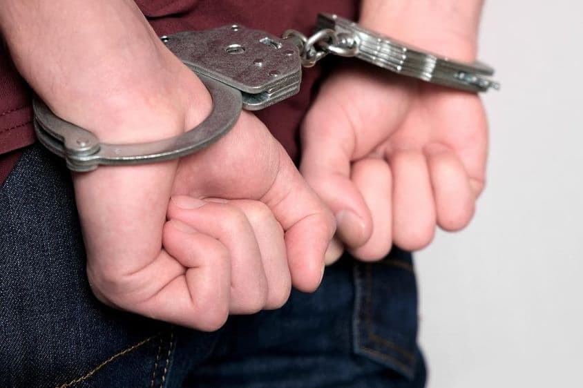 Un criminel menotté et arrêté.