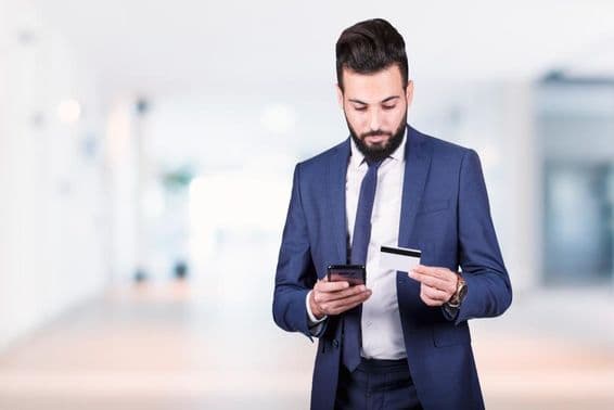 Homme d'affaires arabe tenant un smartphone et une carte de crédit.
