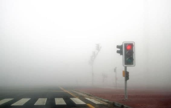 Brouillard sur une route de Dubaï, feu rouge clignotant.