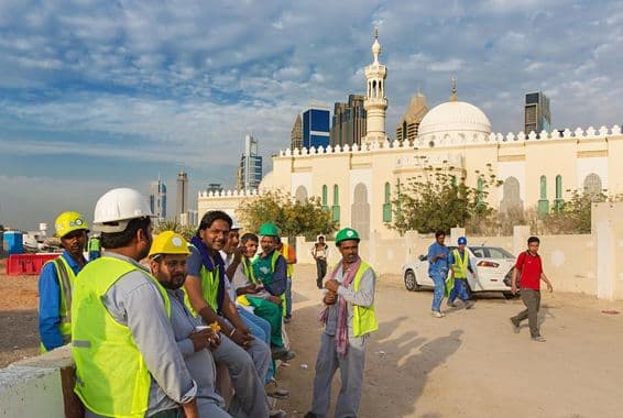 Travailleurs de la construction faisant une pause à côté d'une mosquée dans le centre moderne de Dubaï.